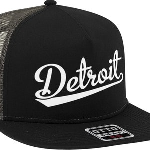 May include: Black and gray trucker hat with a white cursive "Detroit" logo on the front. The hat has a mesh back and a black snap closure.