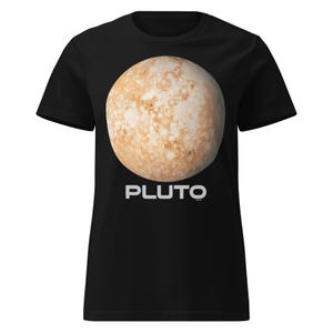 Puede incluir: Camiseta negra con un gráfico detallado de Plutón, el planeta enano, en tonos marrones y beige. La palabra "PLUTO" está impresa en letras blancas debajo. Cuello redondo.