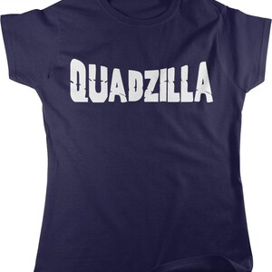 May include: A dark navy blue short-sleeved t-shirt featuring the word QUADZILLA printed in large, white, distressed-style capital letters across the chest. The garment has a crew neckline and a standard fit with hemmed sleeves.