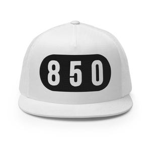 May include: A white trucker hat featuring a structured front panel and a mesh back. Centered on the front is a black horizontal oval patch with rounded ends, displaying the white numerical text 850 in a bold, sans-serif font style.