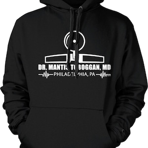 May include: Black hooded sweatshirt with a white graphic. The graphic includes the text "DR. MANTIS TOBOGGAN, MD" and "PHILADELPHIA, PA". The design features a stylized medical symbol.