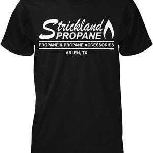 May include: A black short-sleeve t-shirt featuring white screen-printed text that reads Strickland PROPANE, PROPANE & PROPANE ACCESSORIES, and ARLEN, TX, with a flame icon integrated into the letter S and the right side of the logo.