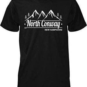 May include: A black short-sleeved t-shirt featuring a white graphic print of mountain peaks and pine trees. The text reads North Conway New Hampshire in a stylized font, positioned directly below the mountain illustration.