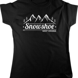 May include: Black t-shirt with a white graphic of mountain peaks, trees, and the word "Snowshoe" above "West Virginia". The design is centered on the front of the shirt.