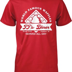 A red t-shirt with a graphic design featuring a waffle and the text "It's Diner" and "World Famous Waffles".