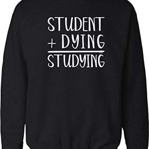May include: Black sweatshirt with the white text "STUDENT + DYING / STUDYING". The crew neck sweatshirt is a casual garment, perfect for students or anyone who appreciates a humorous design.