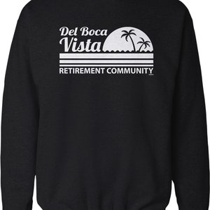May include: Black sweatshirt with white text that reads "Del Boca Vista Retirement Community" and a graphic of a sunset with palm trees.