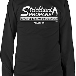 May include: Black long-sleeve t-shirt with a white graphic of the text "Strickland Propane" with a flame design. The text "Propane & Propane Accessories" and "Arlen, TX" are also included in the graphic.