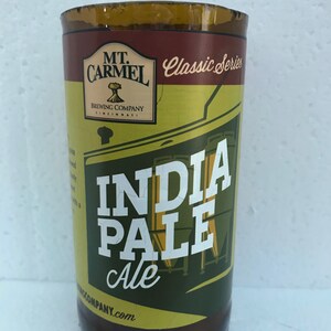 May include: A brown glass bottle with a yellow label that says "Mt. Carmel Brewing Company Cincinnati" and "Classic Series" in a brown banner. The label also features a green illustration of a brewery and the text "India Pale Ale".