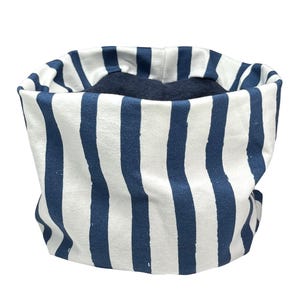 May include: A cylindrical neck warmer featuring a pattern of vertical navy blue stripes on a white background. The interior of the garment is lined with a solid dark navy blue fabric. The text kinnerlee is printed in black in the bottom right corner.