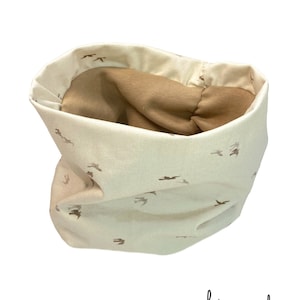 May include: A white fabric neck warmer with a brown bird print and a brown fleece lining.