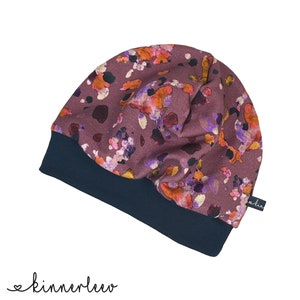 May include: A purple beanie with a floral print and a dark blue brim. The beanie is made of a soft, comfortable fabric.