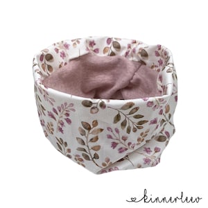 Könnte beinhalten: Ein weißer und rosa Stoff-Halswärmer mit Blumenmuster. Der Halswärmer ist reversibel und hat ein weiches, gemütliches Gefühl.