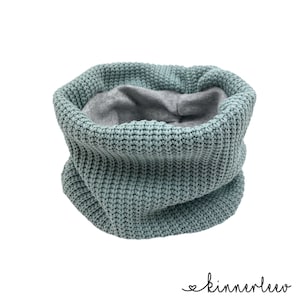 May include: A teal blue knitted neck warmer with a gray fleece lining. The neck warmer is folded and displayed on a white background.