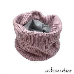 Könnte beinhalten: Ein rosa gestrickter Halsschmuck mit grauem Futter. Der Halsschmuck ist in der Mitte gefaltet und bereit zum Tragen.