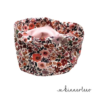 Könnte beinhalten: Ein rosa-weißer, floral bedruckter Halsschoner mit einem rosa Fleecefutter. Der Halsschoner ist aus weichem, bequemem Stoff gefertigt und perfekt, um sich im Winter warm zu halten.