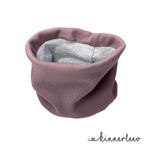 Könnte beinhalten: Ein mauvefarbener gerippter Strick-Halswärmer mit grauem Fleece-Futter. Der Halswärmer ist in der Hälfte gefaltet und liegt auf einem weißen Hintergrund.