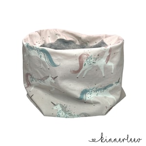 Könnte beinhalten: Ein rosa-grauer Stoff-Halswärmer mit einem Einhorn-Muster. Die Einhörner sind weiß mit rosa, blauen und grünen Akzenten. Der Stoff ist weich und angenehm zu tragen.