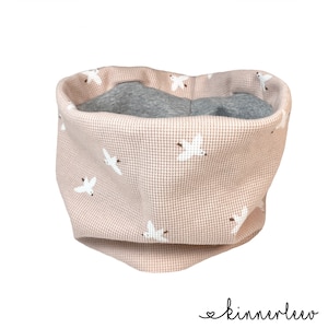 May include: A pink waffle knit neck warmer with a white bird pattern. The neck warmer is lined with grey fleece.