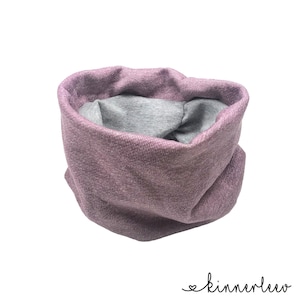 Könnte beinhalten: Ein mauvefarbener und grauer Halswärmer aus weichem Stoff. Die äußere Schicht ist strukturiertes Mauve, während die Innenseite glatt grau ist. Der Halswärmer ist so konzipiert, dass er zur Wärme und zum Komfort um den Hals getragen wird. Der Markenname "kinnerleev" ist kursiv geschrieben.