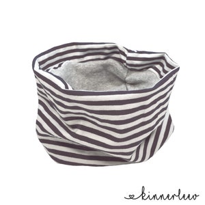 Könnte beinhalten: Ein schwarz-weiß gestreifter Halsschmuck mit grauem Fleecefutter. Der Halsschmuck ist aus weichem, dehnbarem Stoff gefertigt und perfekt, um sich im Winter warm zu halten.