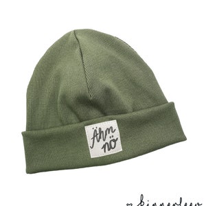 Puede incluir: Un gorro de punto verde con un parche cuadrado blanco que dice "&auml;rm n&ouml;" en letras negras.