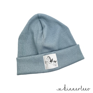 May include: A blue knitted beanie with a white patch featuring a black and white unicorn illustration.