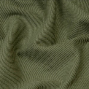 Puede incluir: Primer plano de una tela de punto de canal&eacute; verde. La tela tiene una superficie suave y texturizada.