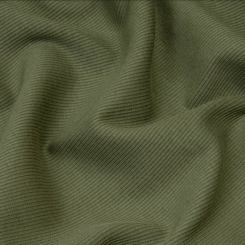 Puede incluir: Primer plano de una tela de punto de canal&eacute; verde. La tela tiene una superficie suave y texturizada.