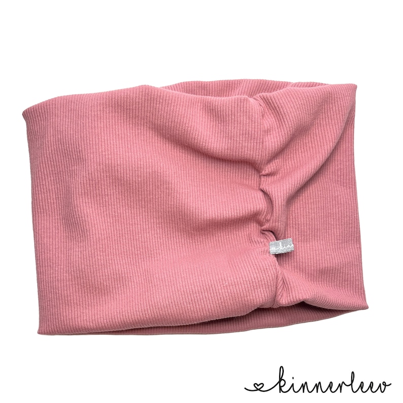 May include: A pink ribbed fabric headband with a small white label that says "kinnerlee" on it.