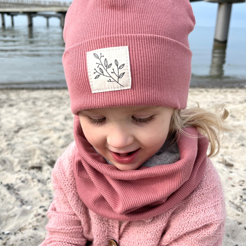 Mädchen mit pinker Rib-Mütze und Loop-Schal am Strang am Meer