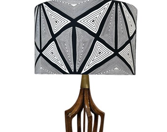 Peut inclure: Une lampe de table moderne du milieu du siècle avec une base en bois et un abat-jour à motifs géométriques noir et blanc.