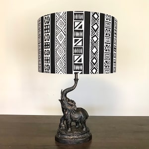 May include: Black and white patterned lampshade with a black elephant base. The lampshade features a geometric pattern with black and white stripes.