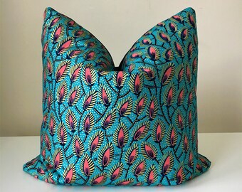 Peut inclure: Un coussin décoratif avec un fond turquoise vif et un motif répété de formes de feuilles roses, dorées et marine. Le coussin a un dos noir uni et est conçu pour la décoration intérieure.