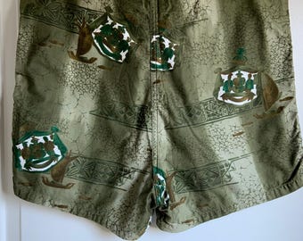 Peut inclure: Short de bain à motif vert et blanc avec un aspect délavé. Le motif présente un dessin répété d'un blason avec une couronne et un navire.