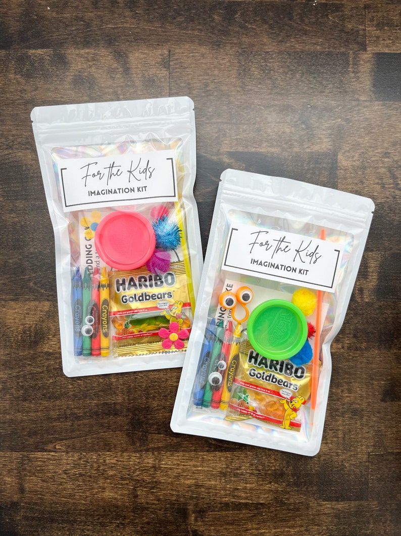 May include: Two clear pouches labeled "For the Kids IMAGINATION KIT" filled with colorful craft supplies. Each kit includes crayons, playdough, googly eyes, pom-poms, and a package of Haribo Goldbears gummy candies.