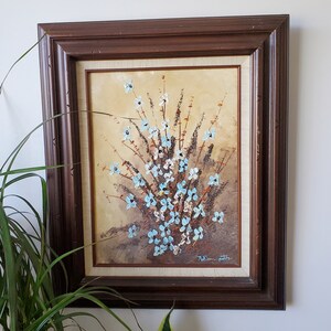 May include: A framed painting of a bouquet of blue and white flowers with brown stems and leaves on a beige background. The painting is signed "T.K. Peterson" in the bottom right corner.
