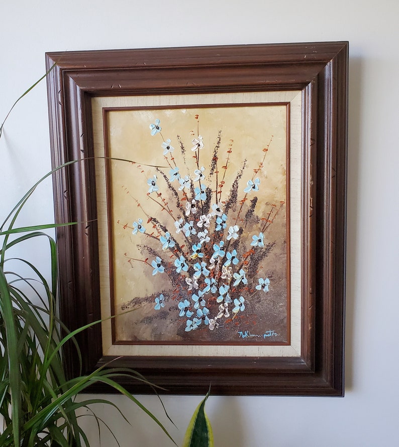 May include: A framed painting of a bouquet of blue and white flowers with brown stems and leaves on a beige background. The painting is signed "T.K. Peterson" in the bottom right corner.