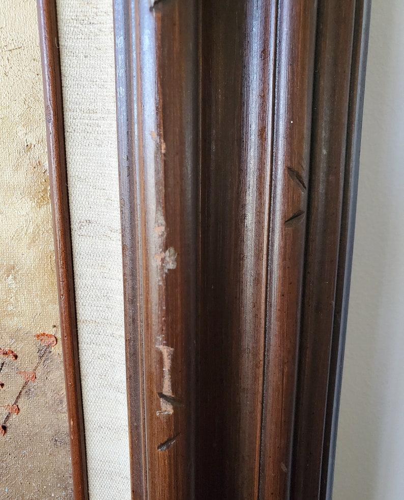May include: Close-up of a dark brown wooden frame with visible wood grain and a few small scratches. The frame is likely for a painting or artwork.