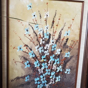 May include: A framed painting of a bouquet of blue and white flowers with brown stems and leaves on a beige background. The painting is signed "M.K. Lam Patti"