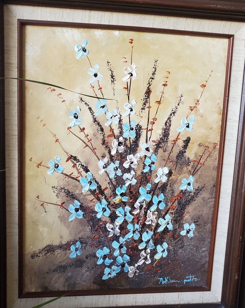 May include: A framed painting of a bouquet of blue and white flowers with brown stems and leaves on a beige background. The painting is signed "M.K. Lam Patti"