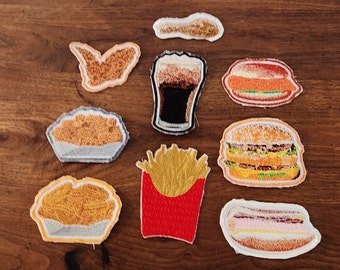 May include: A set of ten embroidered iron-on patches featuring various fast food items, including a burger, fries, chicken nuggets, a hot dog, and a glass of cola.