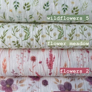 May include: Stack of five white fabric squares with different floral patterns. The patterns include wildflowers, a flower meadow, flowers, raspberries, and blueberries. The fabric squares are labeled with the names of the patterns.