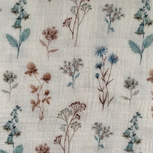 May include: A beige fabric with a repeating pattern of various floral designs in shades of brown, blue, and green. The flowers are stylized and resemble wildflowers.