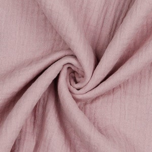 May include: A close-up of a soft, pink fabric with a crinkled texture. The fabric is folded and draped, creating a soft and inviting look.