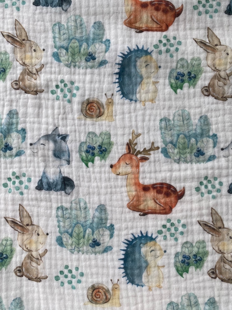 May include: A white fabric with a repeating pattern of woodland animals, including deer, rabbits, hedgehogs, and snails. The animals are drawn in a watercolor style with muted colors.