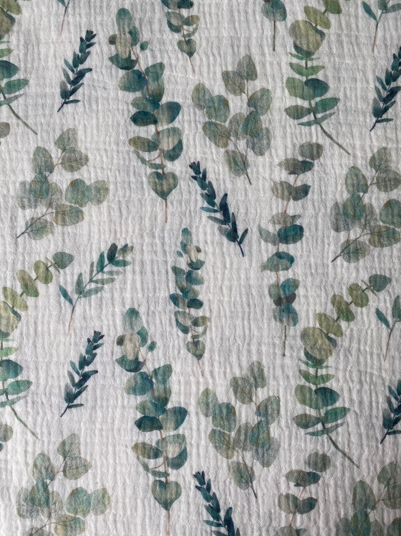 May include: White fabric with a repeating pattern of green and blue watercolor eucalyptus leaves.