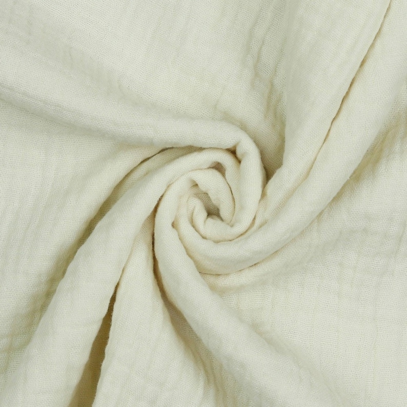 May include: A close-up of a soft, white fabric with a crinkled texture. The fabric is folded and draped, creating a smooth, flowing look.