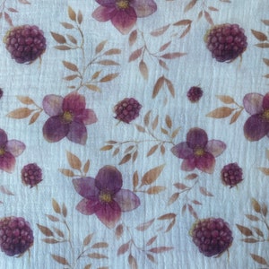 May include: A white fabric with a repeating pattern of purple flowers and dark purple berries. The flowers have five petals and a yellow center. The berries are round and have a textured surface.