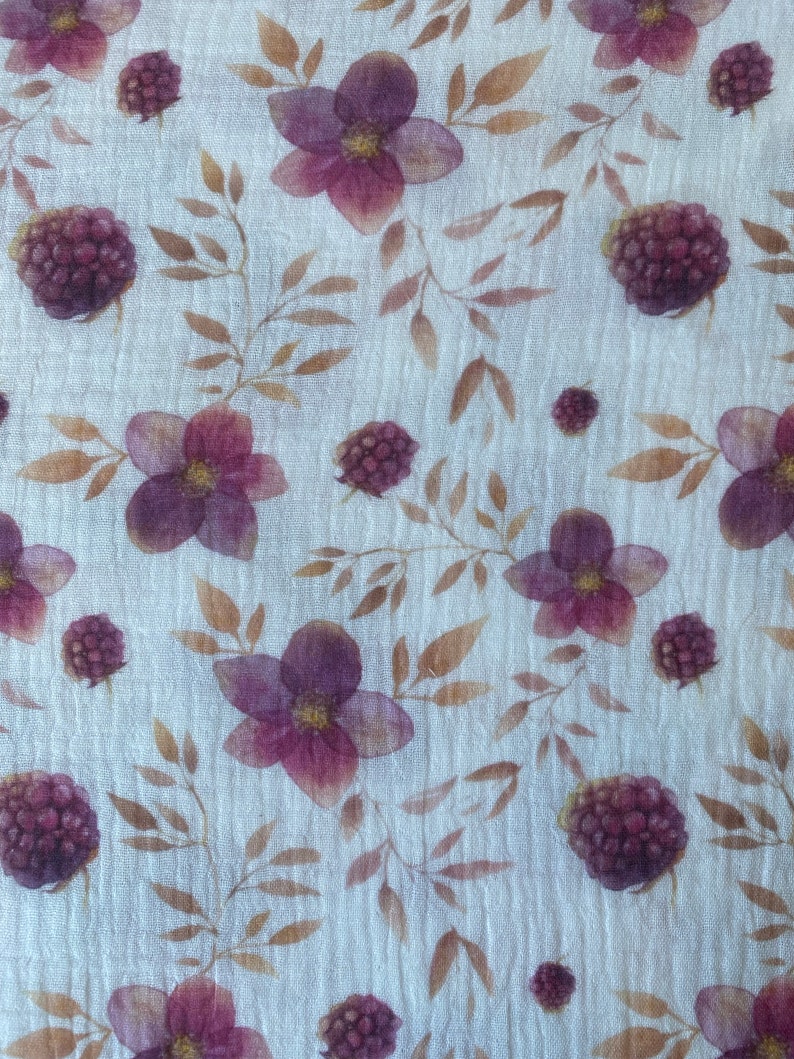May include: A white fabric with a repeating pattern of purple flowers and dark purple berries. The flowers have five petals and a yellow center. The berries are round and have a textured surface.